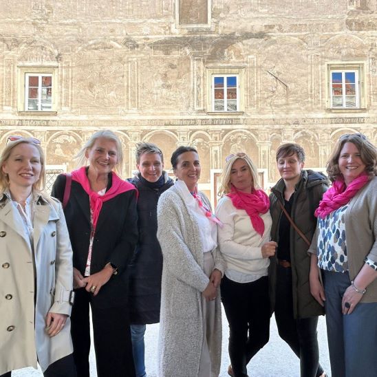 Gruppe der Frauentage Eggenburg mit pinken Schals vor einem historischen Gebäude in Wien.