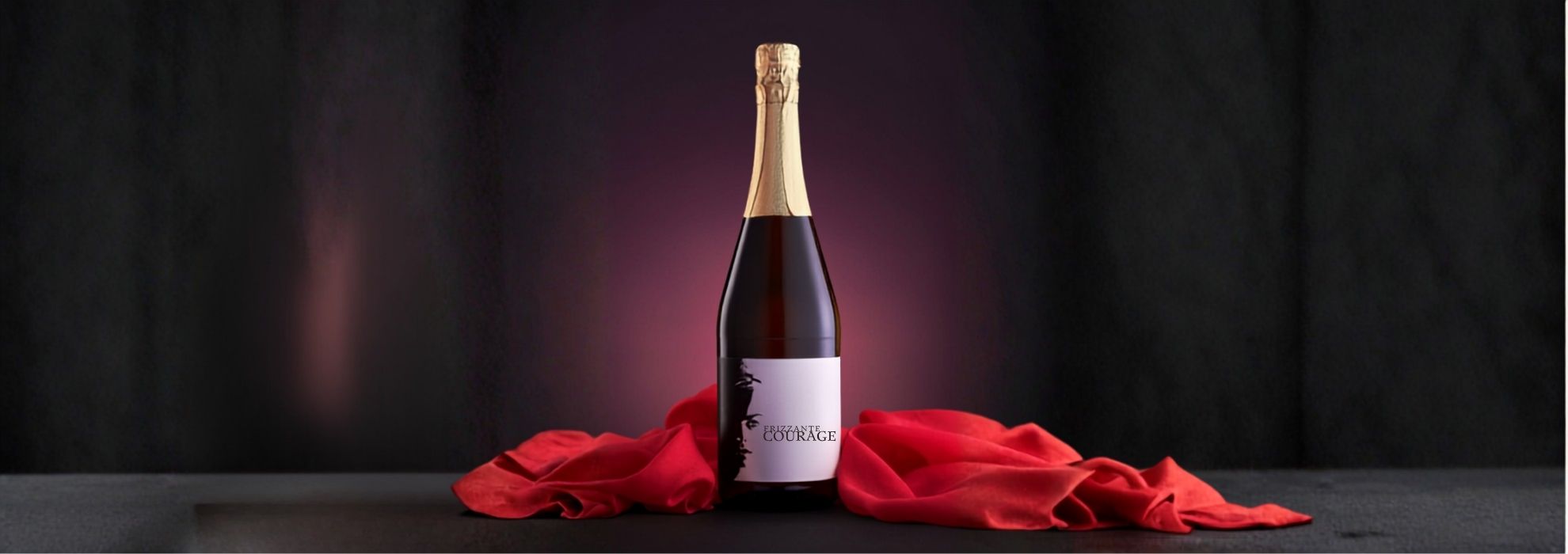 Flasche des Courage Frizzante Grüner Veltliner der Frauentage Eggenburg, elegant inszeniert mit dunklem Hintergrund und rotem Tuch