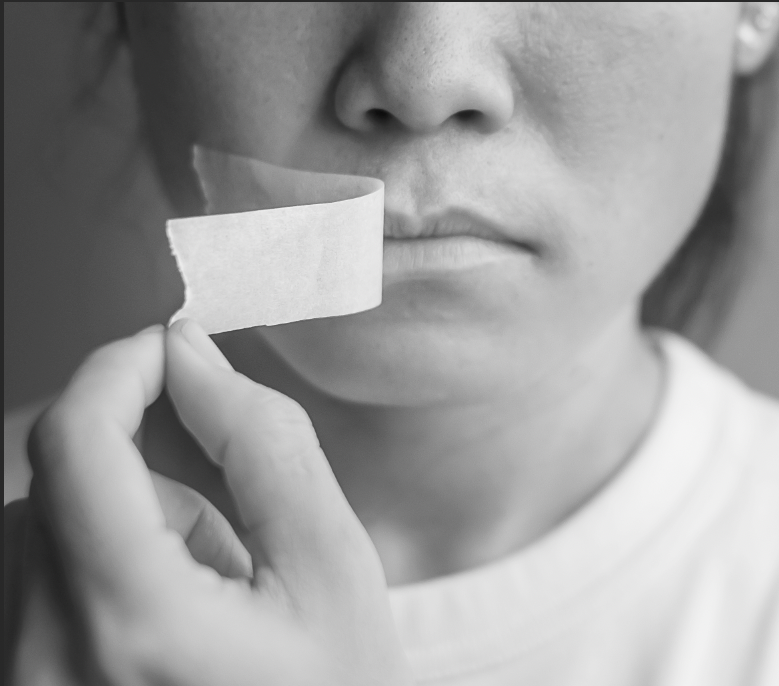 Frau entfernt Klebeband von ihren Lippen – Symbol für Stimme, Selbstbestimmung und Sichtbarkeit von Frauen